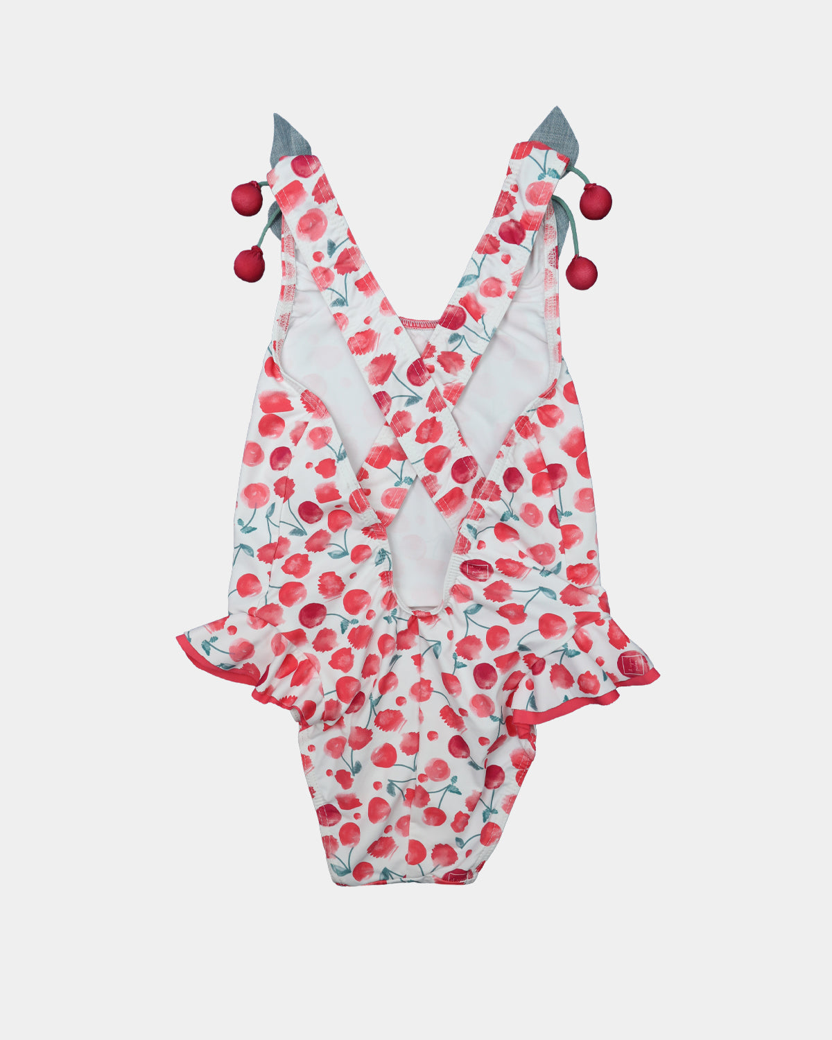 Back view of Al Agua Patos girls cherry swimsuit featuring crisscross straps and decorative cherry pom-pom ties.